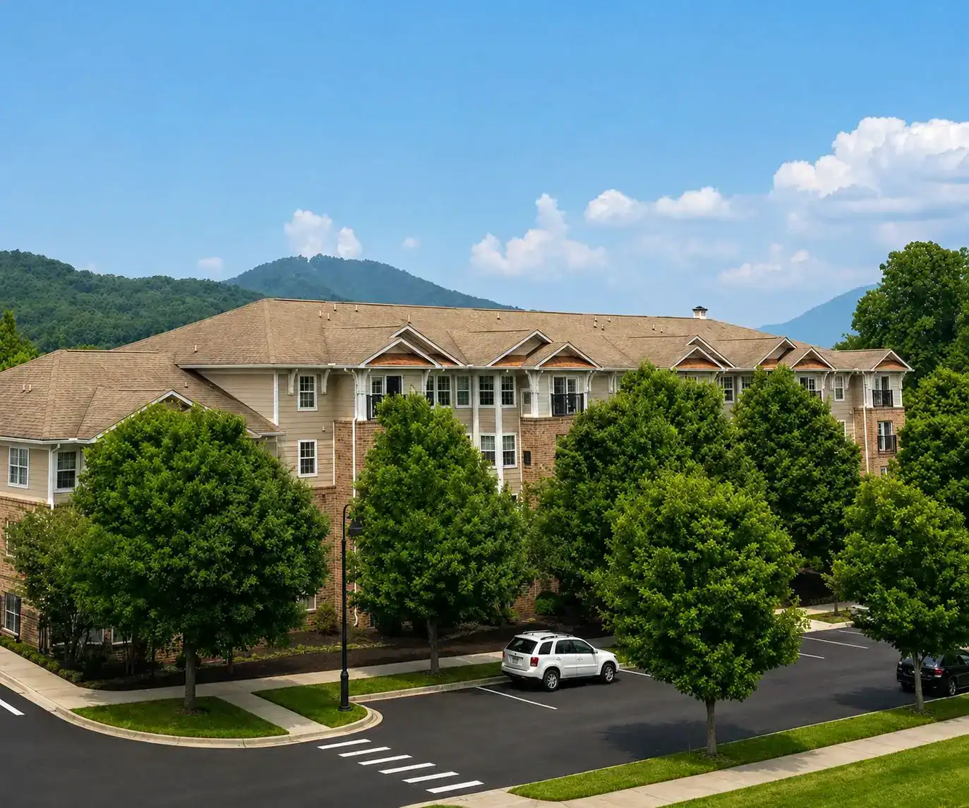 Givens Communities residential building with lush trees and mountain backdrop.